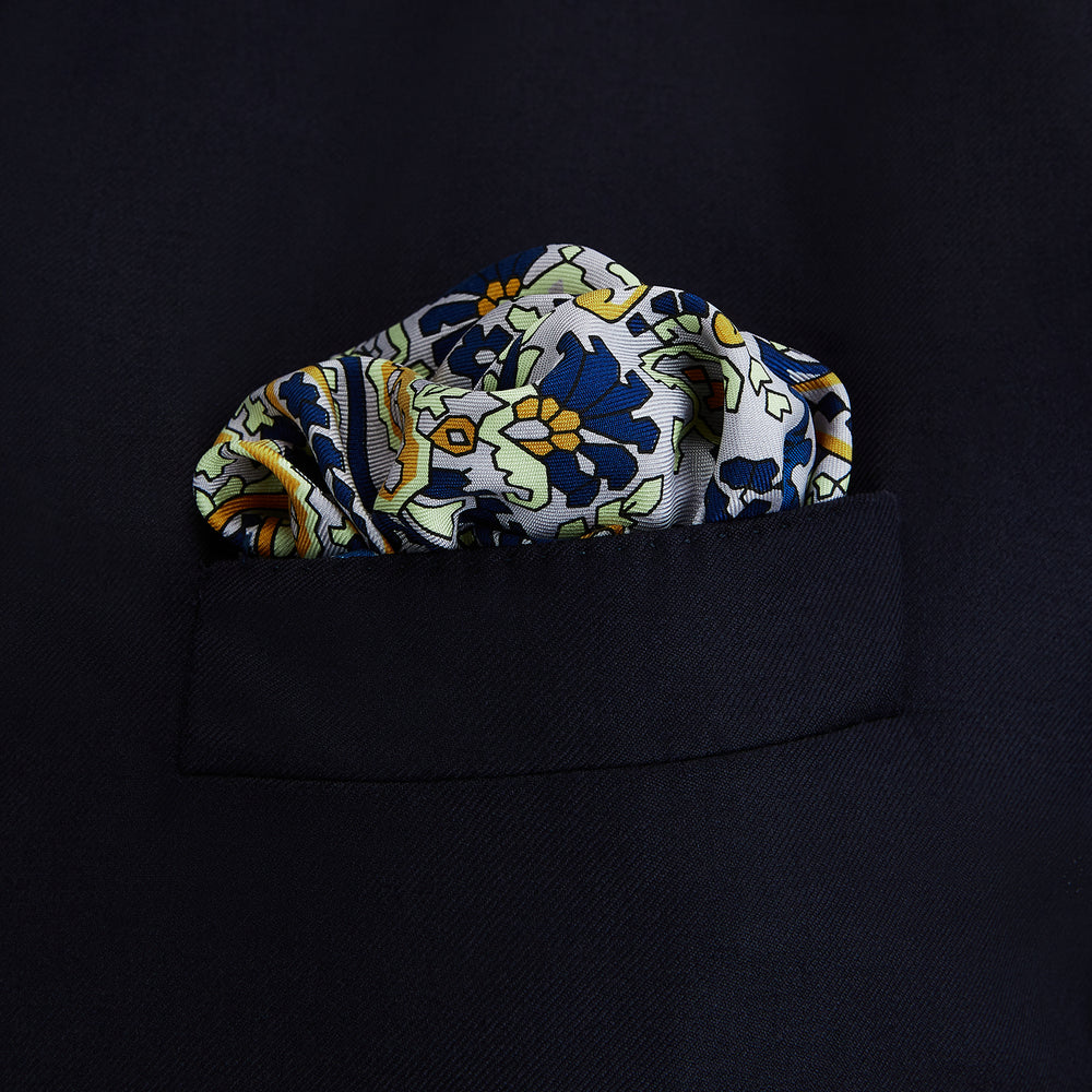The Blue and Yellow Paisley Tiger Silk Pocket Square by Turnbull & Asser features a light blue base with paisley, elephants, tigers, and floral motifs—highlighted by a blue border. An elegant choice to pair with any Turnbull shirt.