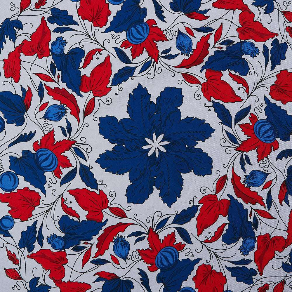 The Blue and Red Foliage Pattern Silk Pocket Square by Turnbull & Asser features intricate symmetrical leaves and flowers in red, blue, and navy on a light grey silk background, creating an elegant circular motif.