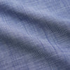 View 4 of product The Turnbull & Asser Blue Chambray Cotton Regular Fit Mayfair Shirt features a subtle textured pattern, pointed T&A collar, and white buttons. Shown here in a light blue shade, laid flat on a white background.
