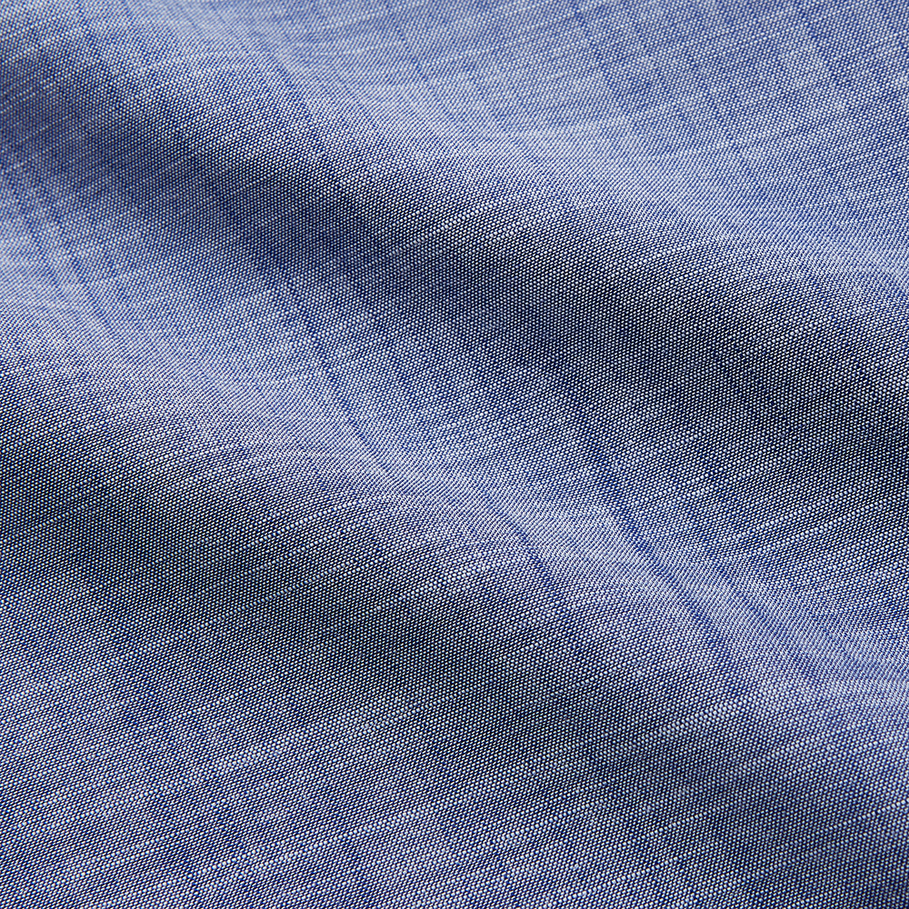 The Turnbull & Asser Blue Chambray Cotton Regular Fit Mayfair Shirt features a subtle textured pattern, pointed T&A collar, and white buttons. Shown here in a light blue shade, laid flat on a white background.