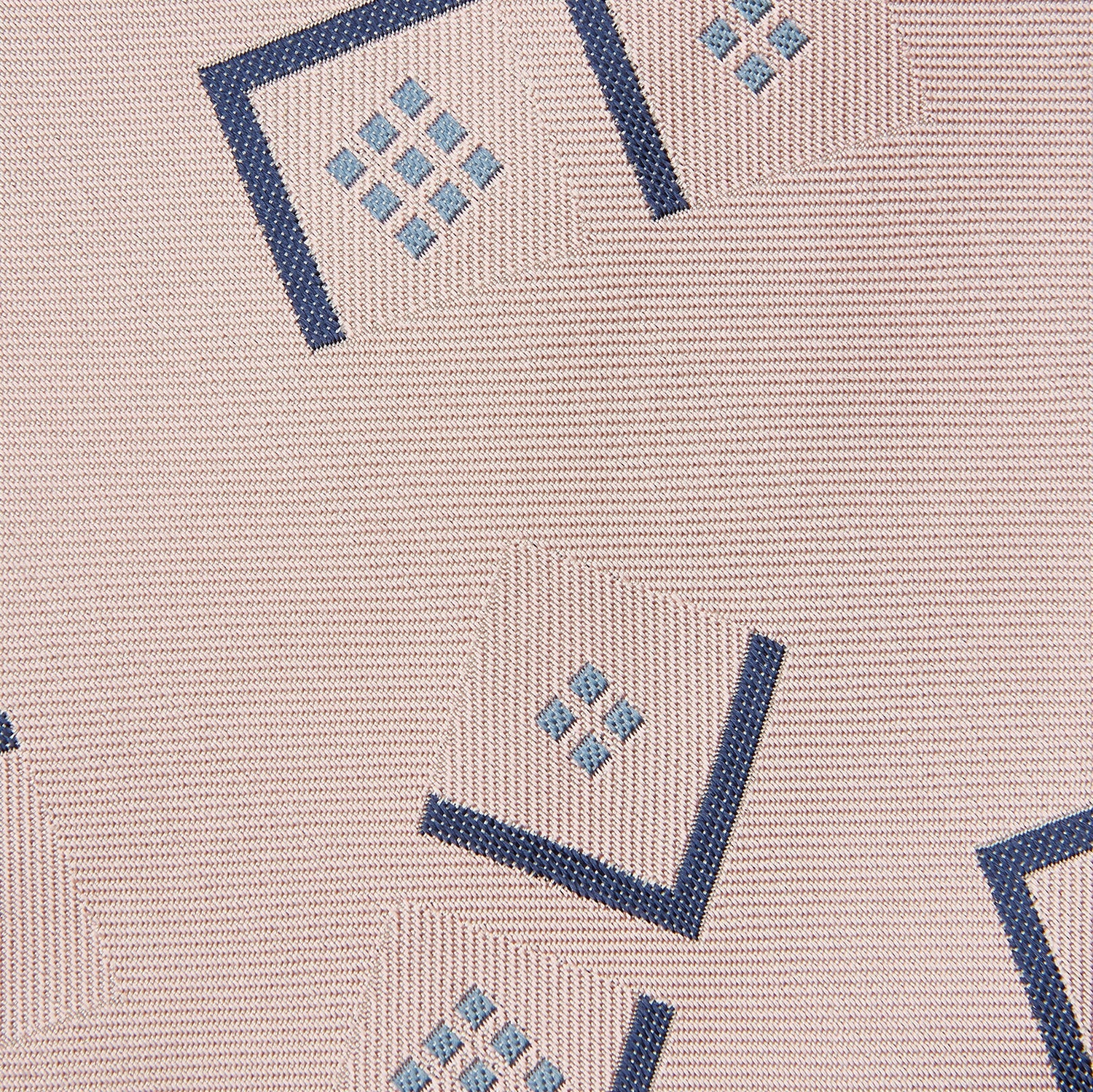 View 2 of product The Turnbull & Asser Pink Graphic Deco Silk Tie features blue geometric and square patterns on pale pink silk, shown rolled with the pointed end facing forward.