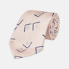 View 1 of product The Turnbull & Asser Pink Graphic Deco Silk Tie features blue geometric and square patterns on pale pink silk, shown rolled with the pointed end facing forward.