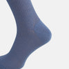 View 4 of product A single Powder Blue Mid-Length Merino Sock by Turnbull & Asser stands upright against a white background, showcasing its smooth texture and subtle vertical lines, with a length that reaches just below the knee.