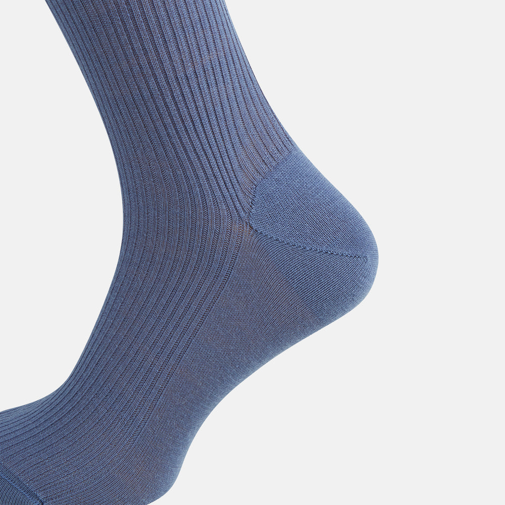 A single Powder Blue Mid-Length Merino Sock by Turnbull & Asser stands upright against a white background, showcasing its smooth texture and subtle vertical lines, with a length that reaches just below the knee.