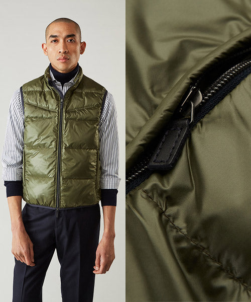 A man wearing an olive green puffer vest over a striped shirt and dark pants; next to him is a close-up of the vests zipper and fabric texture.
