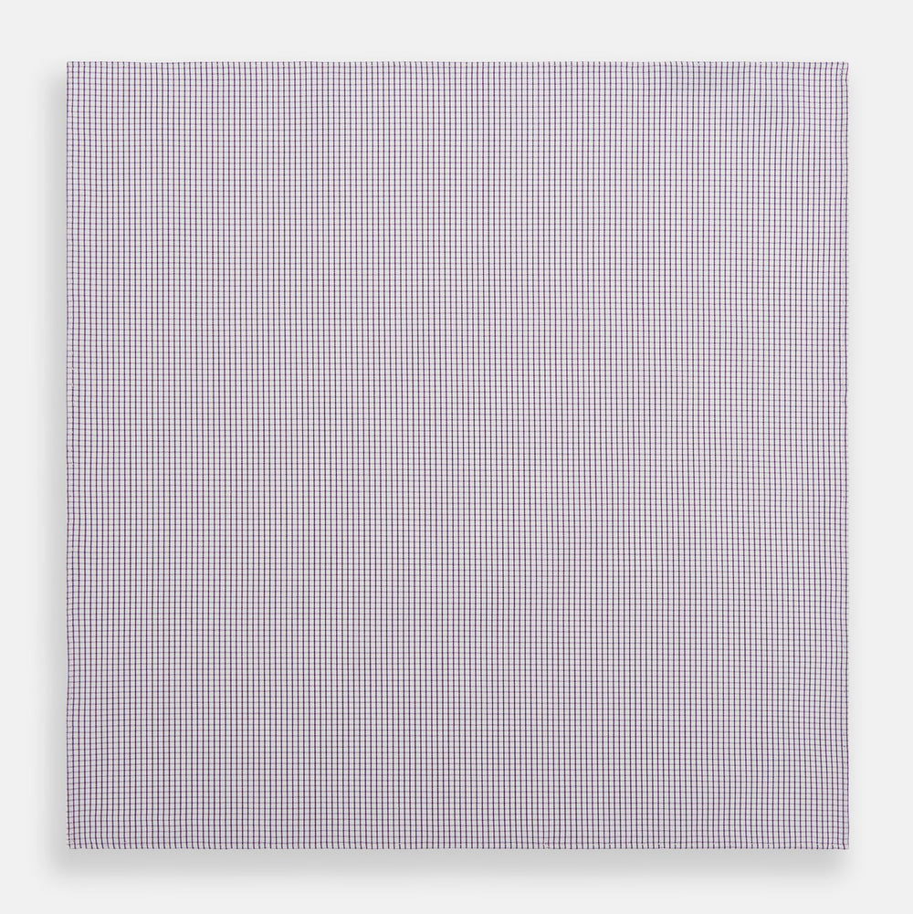 The Turnbull & Asser Hand Rolled Purple Graph Check Handkerchief features a purple checkered grid pattern on white cotton, neatly folded and displayed on a plain surface—a refined accessory for any formal occasion.