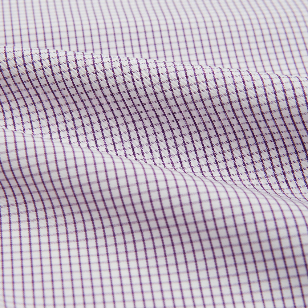 The Turnbull & Asser Hand Rolled Purple Graph Check Handkerchief features a purple checkered grid pattern on white cotton, neatly folded and displayed on a plain surface—a refined accessory for any formal occasion.