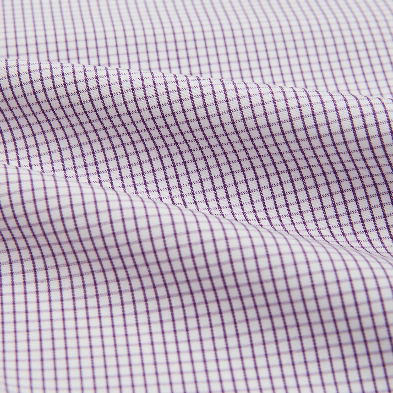 View 4 of product The Turnbull & Asser Hand Rolled Purple Graph Check Handkerchief features a purple checkered grid pattern on white cotton, neatly folded and displayed on a plain surface—a refined accessory for any formal occasion.