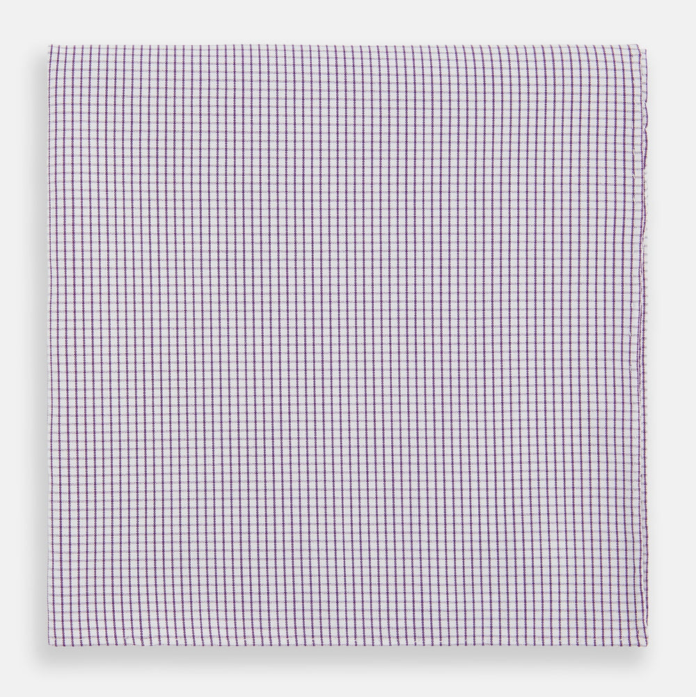 The Turnbull & Asser Hand Rolled Purple Graph Check Handkerchief features a purple checkered grid pattern on white cotton, neatly folded and displayed on a plain surface—a refined accessory for any formal occasion.