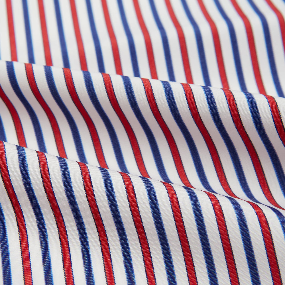 The Hand Rolled Red and Blue Track Stripe Handkerchief by Turnbull & Asser features vertical red, blue, and white stripes—a refined cotton accessory with a visible seam, ideal for formal occasions.