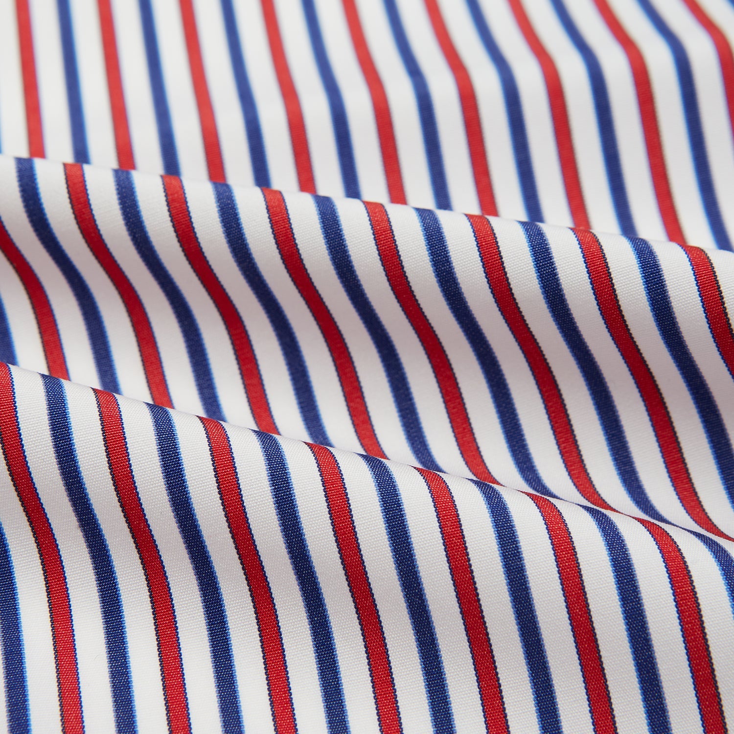 View 4 of product The Hand Rolled Red and Blue Track Stripe Handkerchief by Turnbull & Asser features vertical red, blue, and white stripes—a refined cotton accessory with a visible seam, ideal for formal occasions.