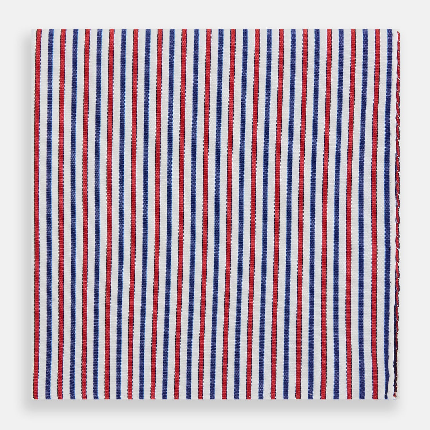 View 1 of product The Hand Rolled Red and Blue Track Stripe Handkerchief by Turnbull & Asser features vertical red, blue, and white stripes—a refined cotton accessory with a visible seam, ideal for formal occasions.