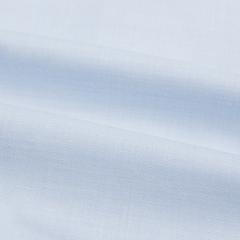 The Turnbull & Asser Blue Cashmerello Mayfair Shirt is a light blue cotton-cashmere blend with long sleeves, pointed collar, white buttons, and buttoned cuffs, shown on a plain white background.