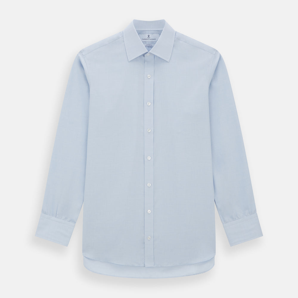 The Turnbull & Asser Blue Cashmerello Mayfair Shirt is a light blue cotton-cashmere blend with long sleeves, pointed collar, white buttons, and buttoned cuffs, shown on a plain white background.
