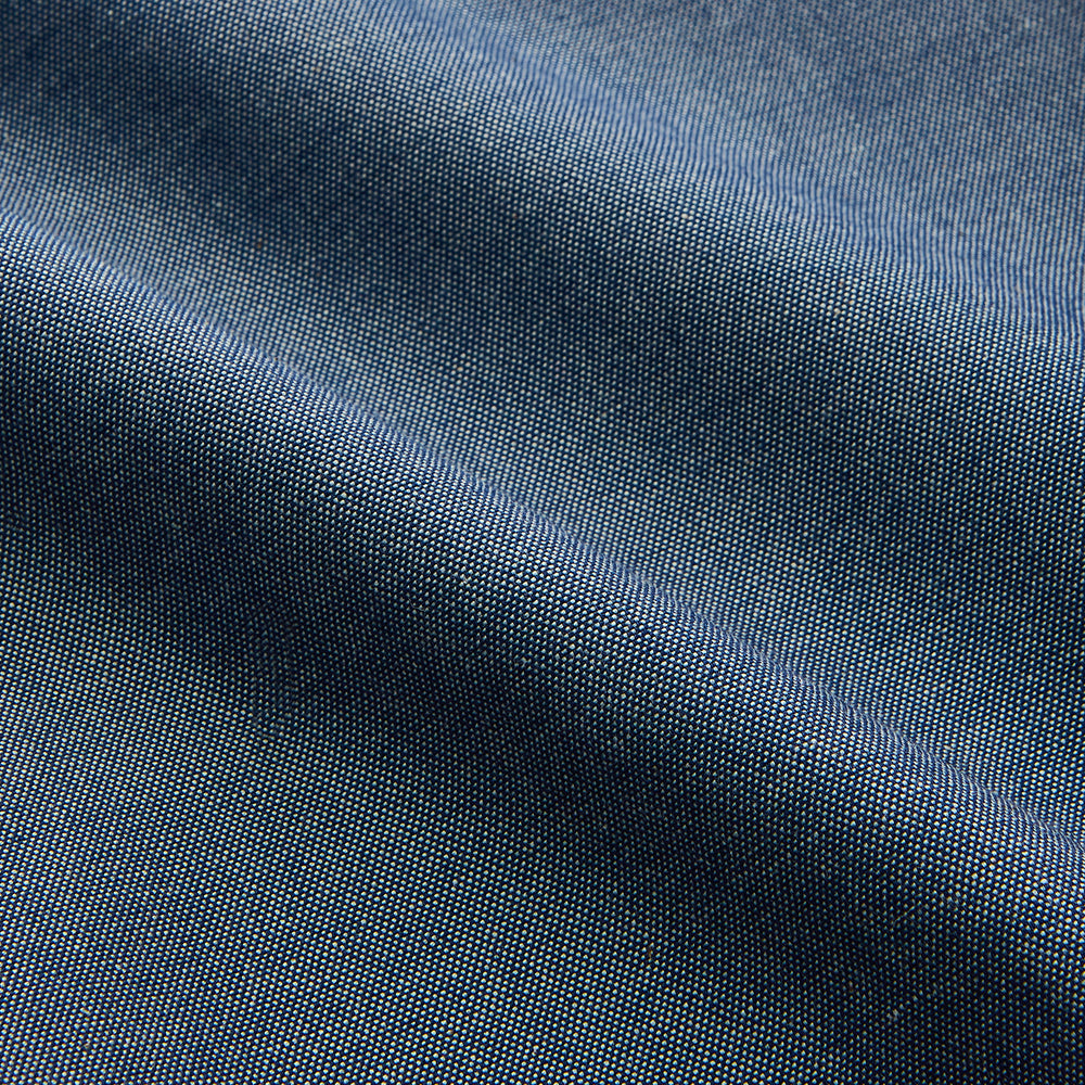 The Turnbull & Asser Blue Chambray Weekend Fit Nevis Cotton Shirt features a Dorset collar, 1-button cuffs, and smart-casual tailoring, shown laid flat on a white background.