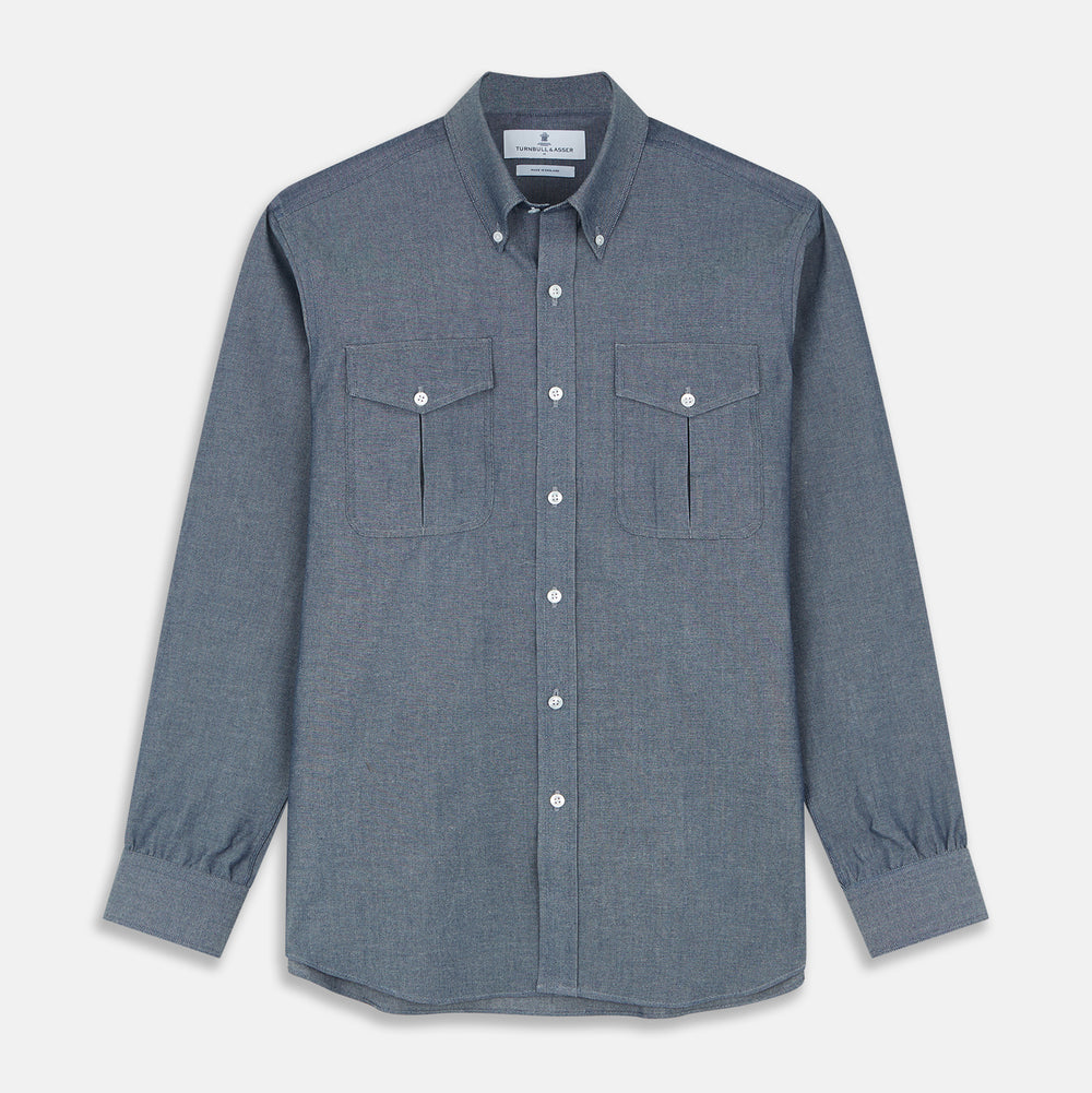 The Turnbull & Asser Blue Chambray Weekend Fit Nevis Cotton Shirt features a Dorset collar, 1-button cuffs, and smart-casual tailoring, shown laid flat on a white background.