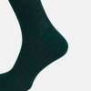 View 4 of product A single Turnbull & Asser Petrol Green Mid-Length Merino Sock stands upright on a plain white background, showcasing its ribbed texture and signature rounded toe and heel.