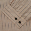 View 5 of product An older man in a light hat, Turnbull & Asser Beige Stripe Cotton Holiday Fit Shirt with Revere Collar & Single Button Cuff, and white pants leans casually against a tall concrete pillar outdoors, greenery blurred behind him.