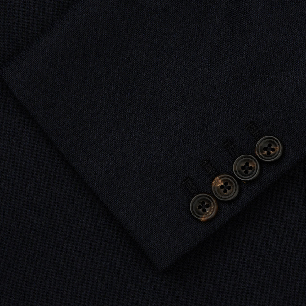 The Midnight Navy Wool Barrington Blazer by Turnbull & Asser features a single-breasted design with notched lapels, three front flap pockets, one chest pocket, and a two-button closure, neatly laid flat against a white background.