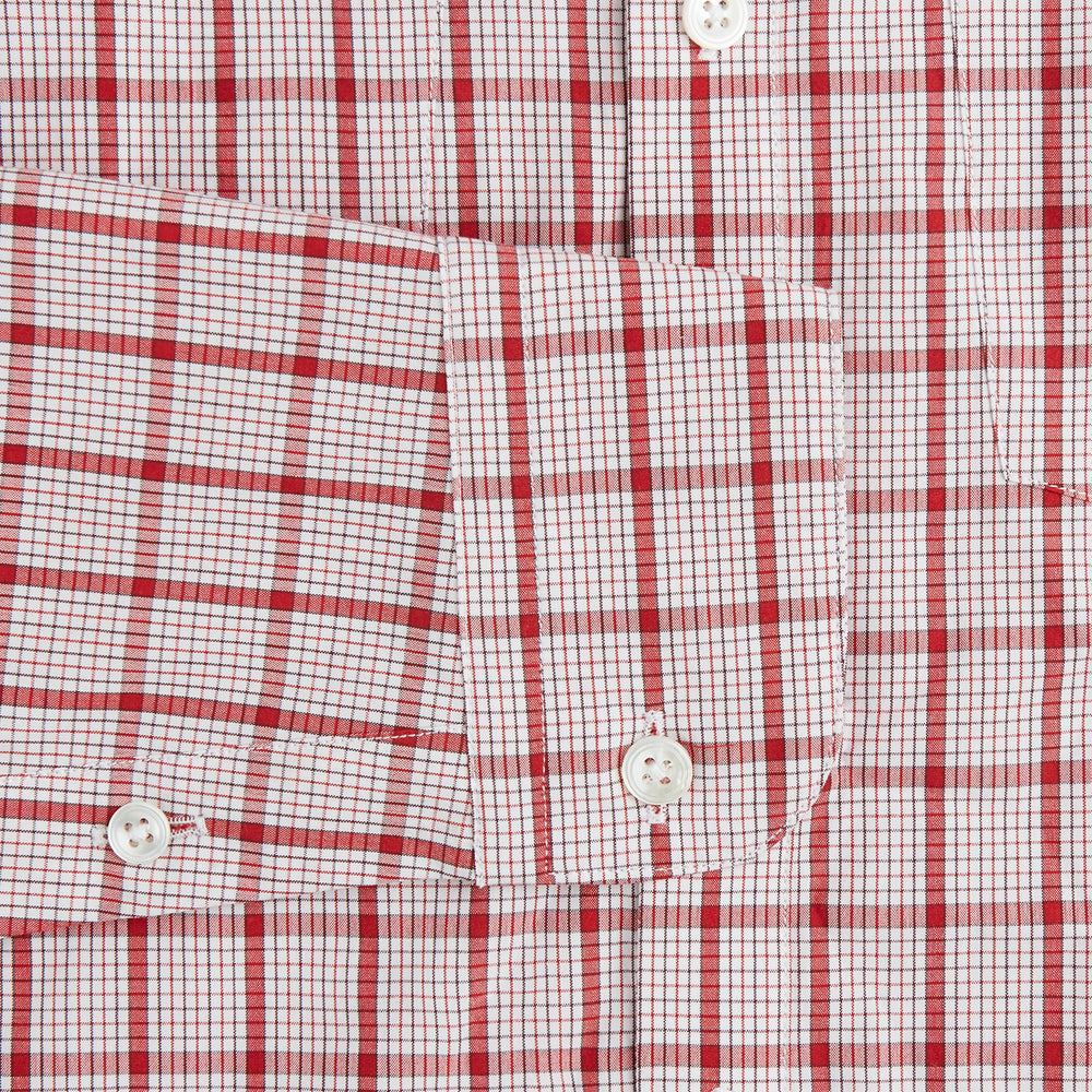 The Turnbull & Asser Red Graph Overlay Check Piccadilly Shirt is a cotton, long-sleeve button-up with a white base, red graph check pattern, collar, two chest flap pockets, and white buttons on the front and cuffs.