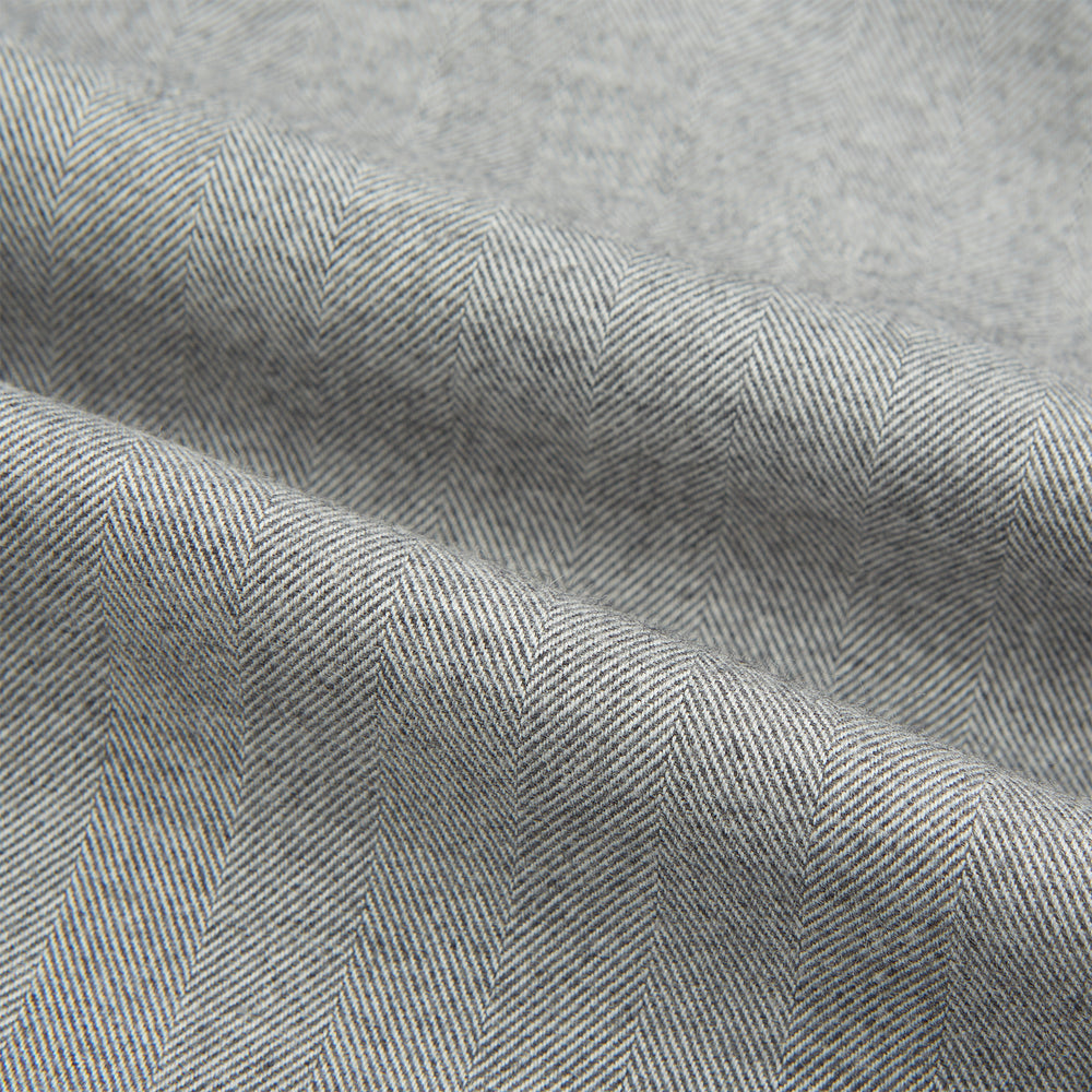 The Turnbull & Asser Grey Herringbone Chelsea Shirt features long sleeves, a chest pocket, classic collar, and buttoned cuffs, adding refined style to smart-casual outfits—shown here against a plain white background.