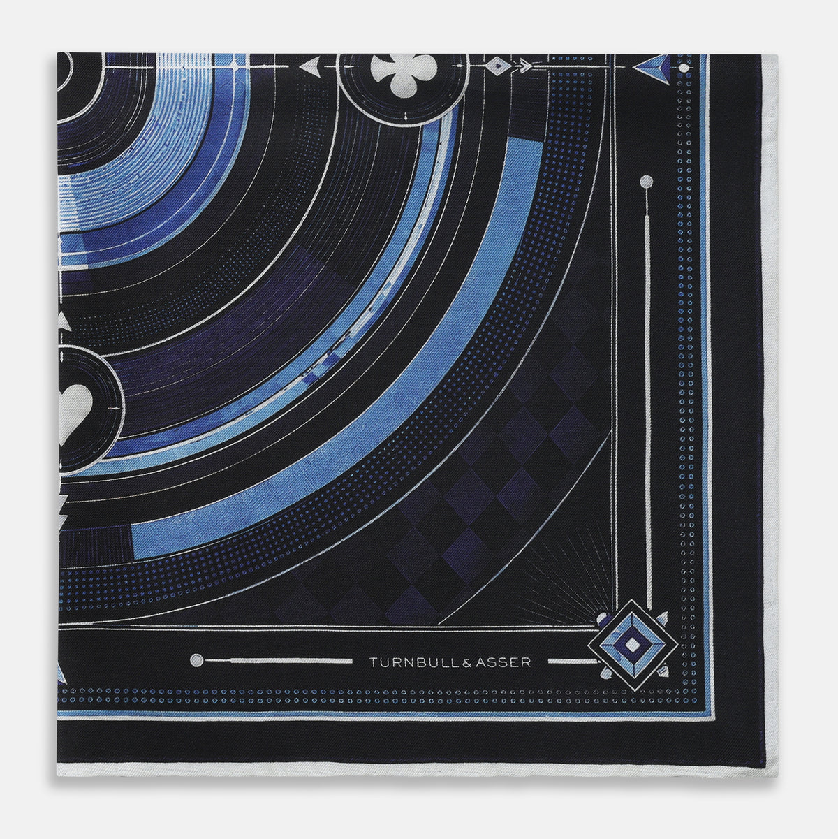 View 3 of product Presenting the Casino Royale Midnight Blue Target Pocket Square in Silk from Turnbull & Asser UK—a luxurious silk square scarf adorned with concentric circles in rich midnight blue and black, accented by playing card suit symbols (spade, diamond, club, heart) at each cardinal point and striking geometric patterns in the corners. This elegant accessory is perfect for adding a touch of sophisticated intrigue to your ensemble.