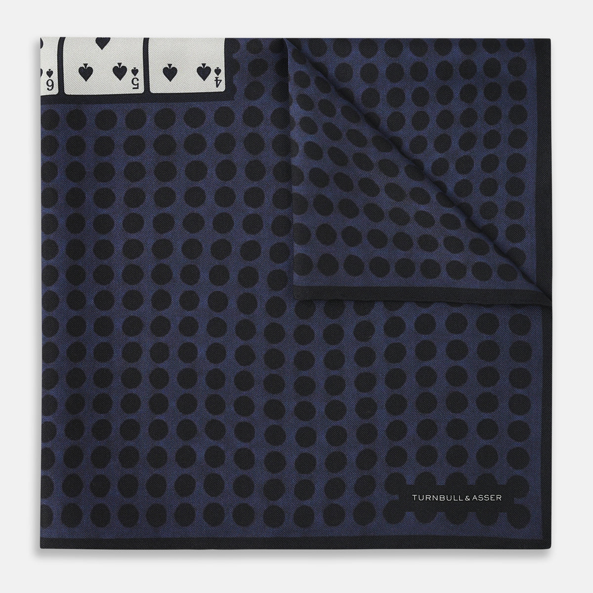 View 3 of product The Casino Royale Midnight Blue Straight Flush Pocket Square in Silk by Turnbull & Asser UK features a rich midnight blue background adorned with a black dotted pattern and showcases five playing cards—the 10, 9, 8, 7, and 6 of spades—arranged in a row at the center for an elegant straight flush design inspired by classic casino style.