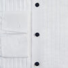 View 4 of product The Casino Royale White Dress Shirt in Cotton by Turnbull & Asser UK is a long-sleeve white dress shirt, crafted from crisp white cotton poplin with a pleated bib front, black buttons, and a classic collar, shown laid flat on a white background.