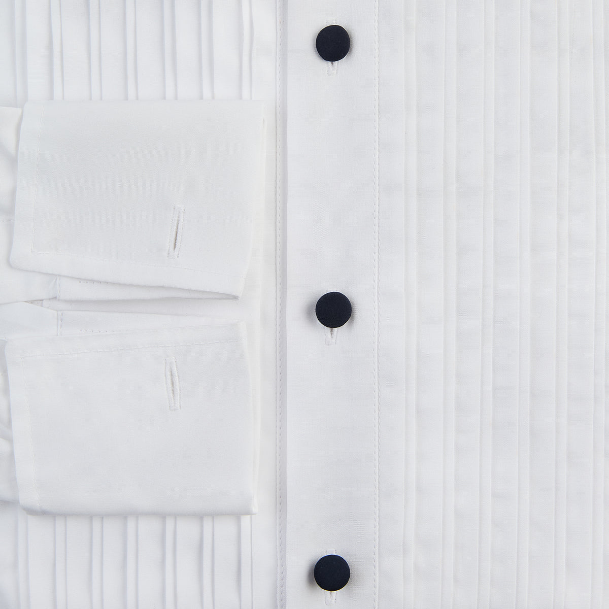 View 4 of product The Casino Royale White Dress Shirt in Cotton by Turnbull & Asser UK is a long-sleeve white dress shirt, crafted from crisp white cotton poplin with a pleated bib front, black buttons, and a classic collar, shown laid flat on a white background.