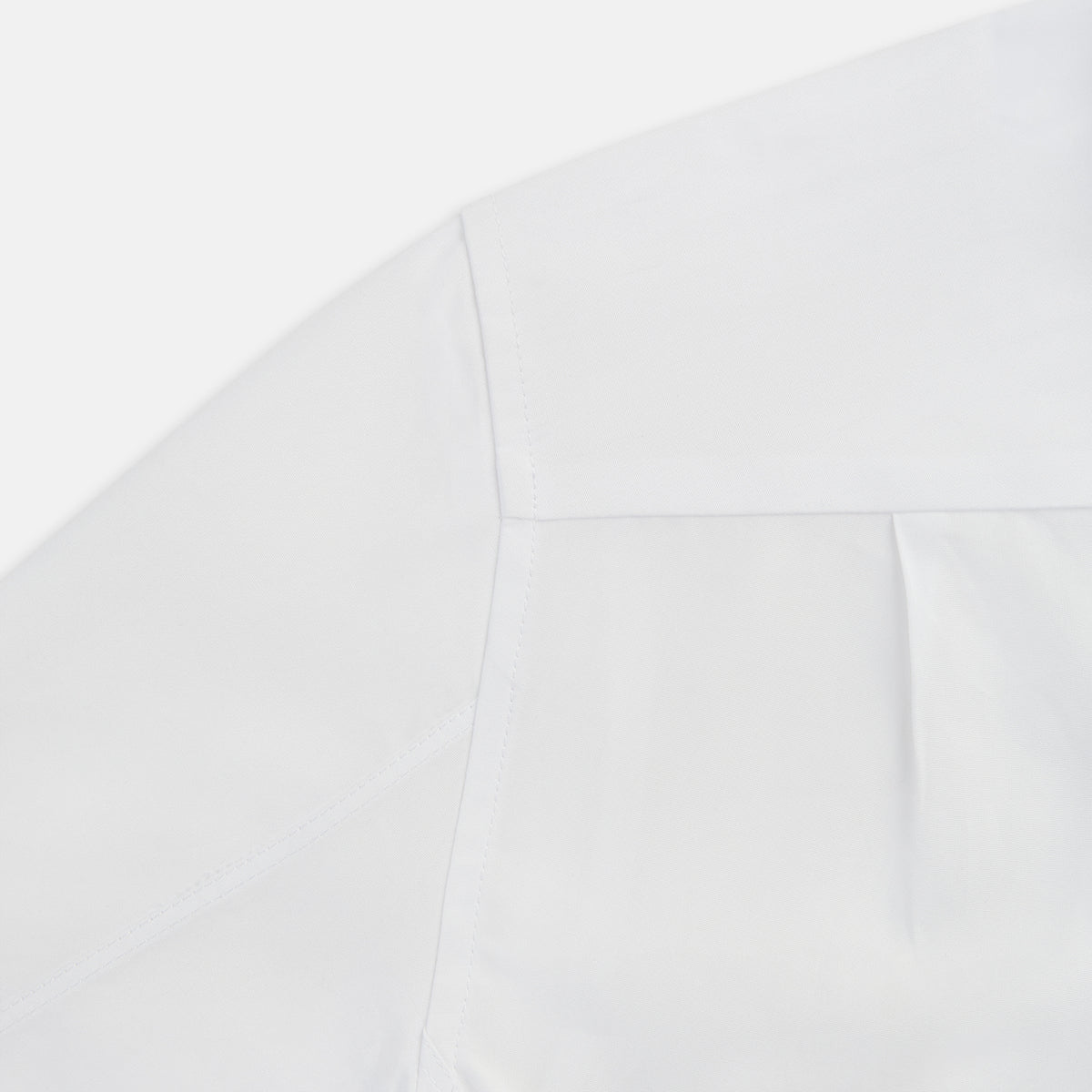 View 6 of product The Casino Royale White Dress Shirt in Cotton by Turnbull & Asser UK is a long-sleeve white dress shirt, crafted from crisp white cotton poplin with a pleated bib front, black buttons, and a classic collar, shown laid flat on a white background.
