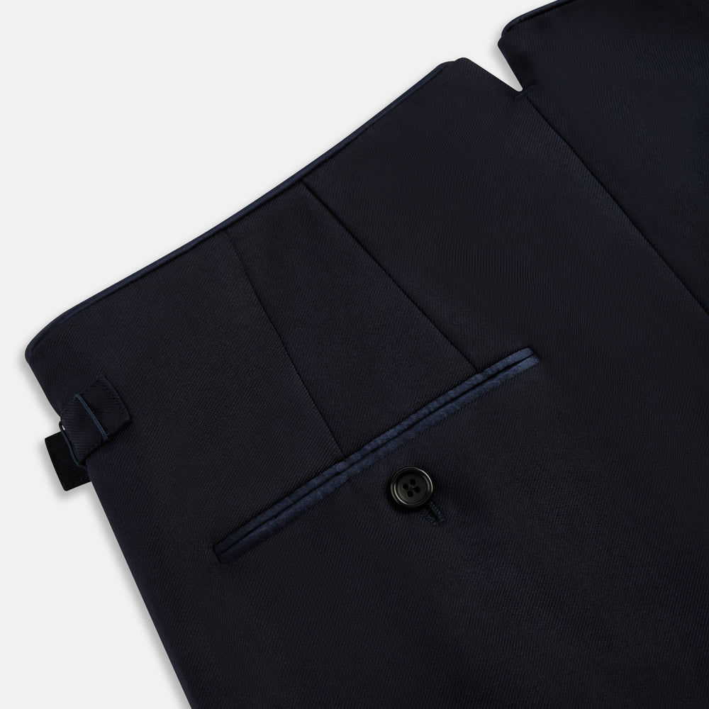 The Casino Royale Midnight Blue Tuxedo Trousers in Wool by Turnbull & Asser UK are shown from the back, expertly crafted from virgin wool in a signature tuxedo style, featuring two buttoned back pockets and adjustable side tabs at the waistband.