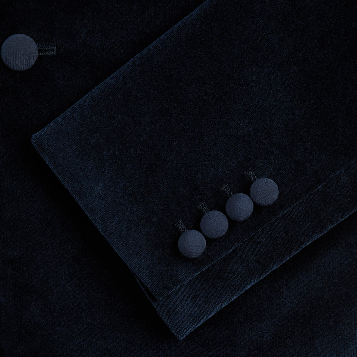 View 4 of product Turnbull & Asser UK’s Casino Royale Midnight Blue Tuxedo Jacket in Cotton Velvet, featuring a single button closure and a luxurious silk-satin shawl lapel, is showcased against a plain white background.