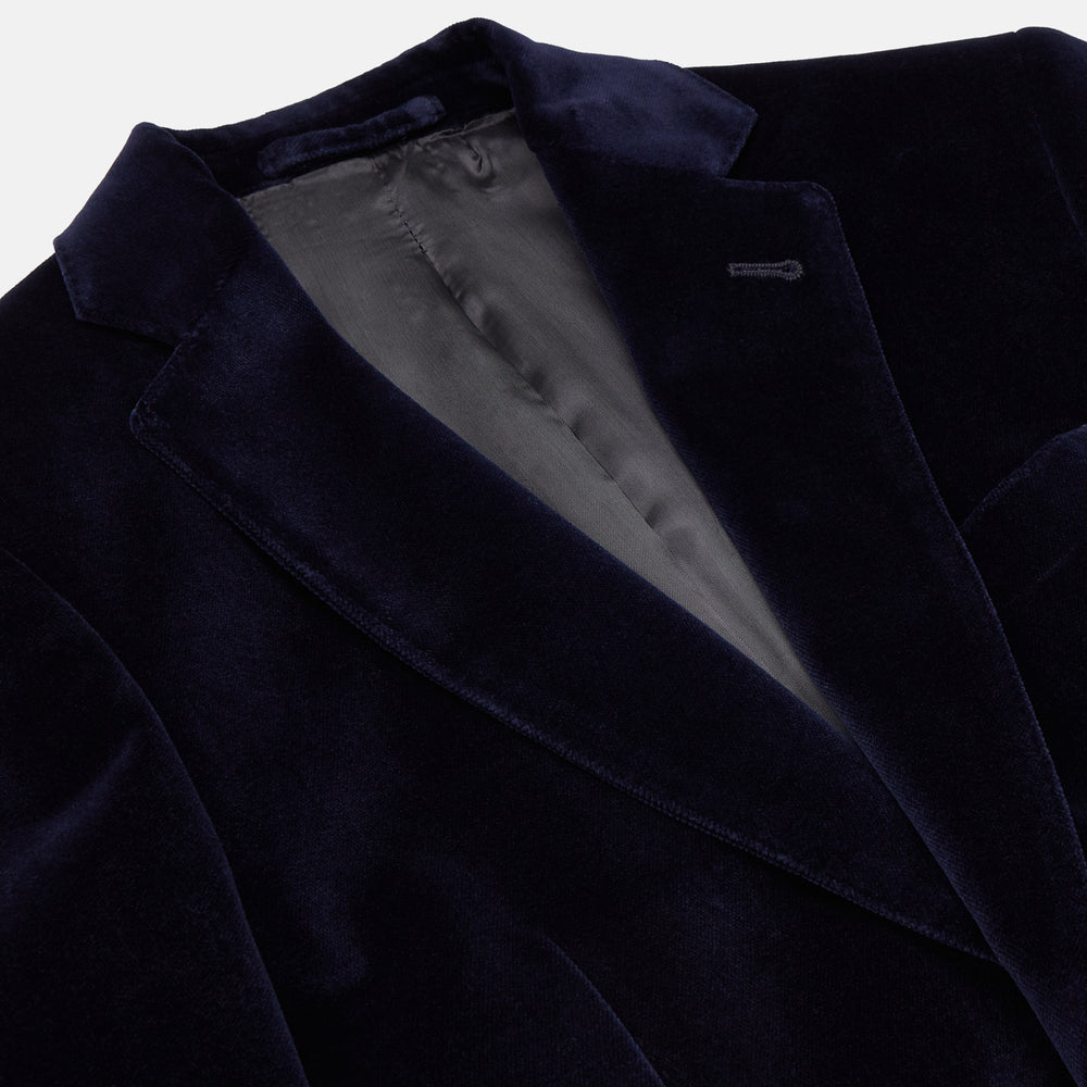 The Turnbull & Asser Navy Velvet Jacket features a classic fit, single-breasted style, notched lapels, two flap pockets, chest pocket, and single button closure. Made in Italy; shown on a plain white background.