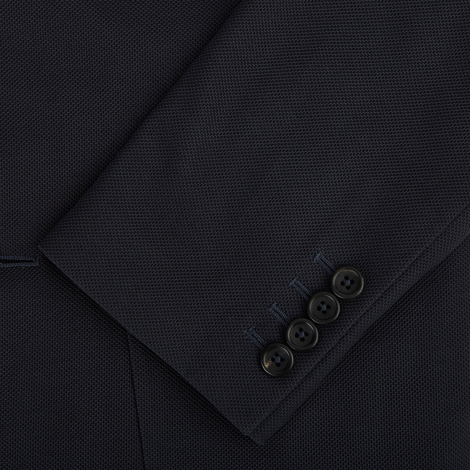 View 4 of product The Charcoal Knitted London Blazer by Turnbull & Asser is a men's single-breasted formal jacket with two buttons, notched lapels, and two front patch pockets, shown against a plain white background.