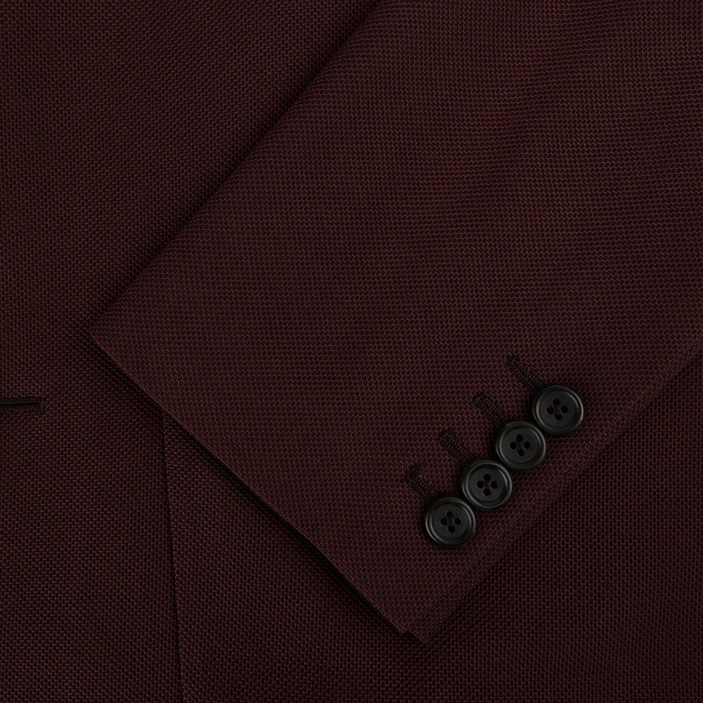 The Turnbull & Asser Burgundy Knitted London Blazer features notch lapels, two front buttons, flap pockets, and a welt chest pocket—ideal for spring and summer—shown against a plain white background.