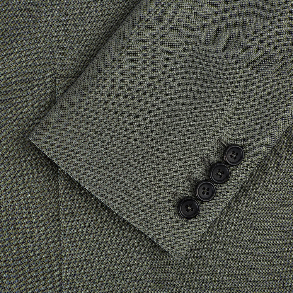 The Turnbull & Asser UK Sage Silk & Cotton Bath Blazer is a single-breasted Italian-tailored piece in olive green, featuring notch lapels, two front patch pockets, a chest pocket, and two buttons, shown on a plain white background.