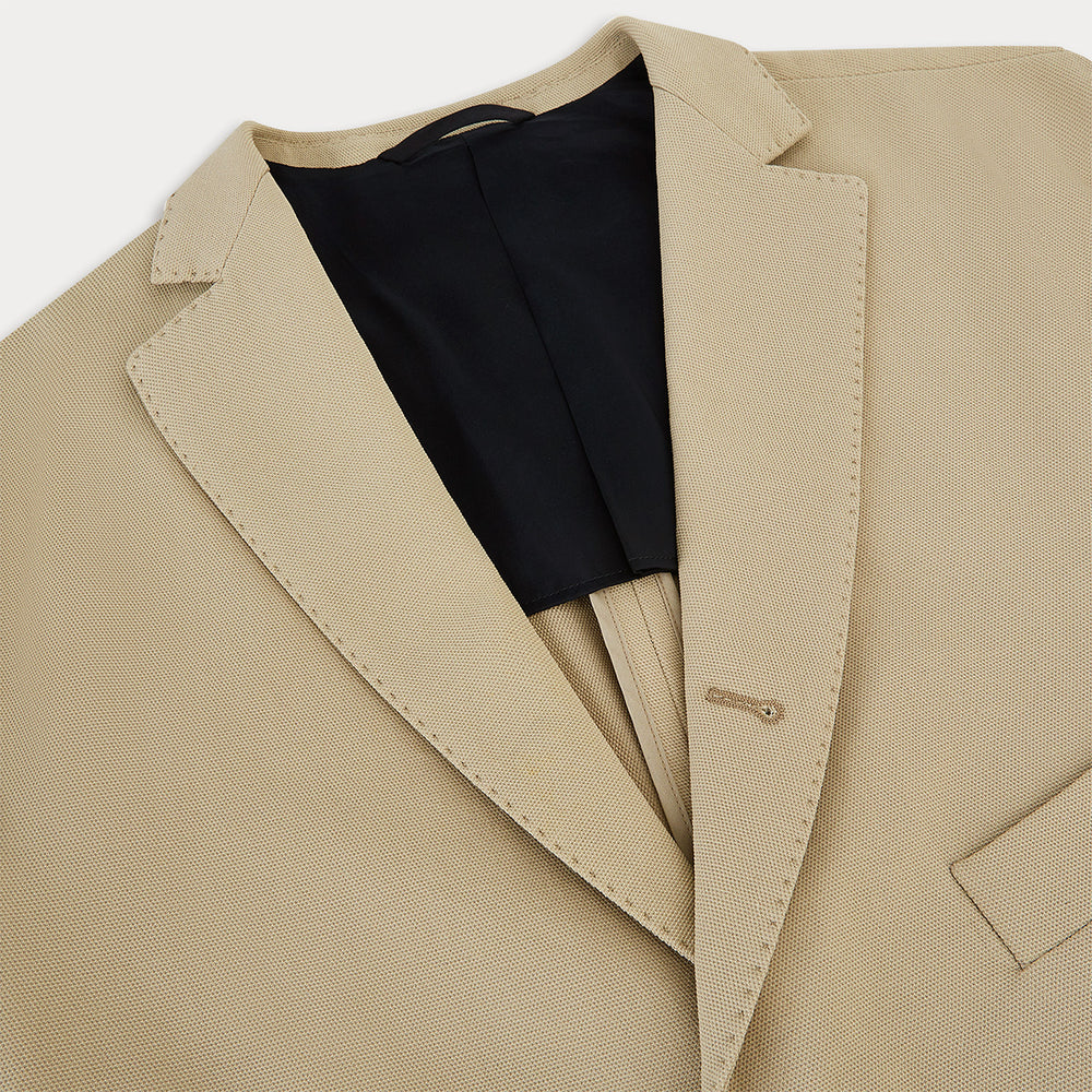 Riviera Sand Oversized Blazer in Cotton by Turnbull & Asser UK, featuring two spacious front pockets, a single chest pocket, and a classic notched lapel. Expertly tailored from premium cotton-nylon stretch fabric, this blazer is shown front-facing against a clean white background—an essential piece for achieving effortless sophistication.