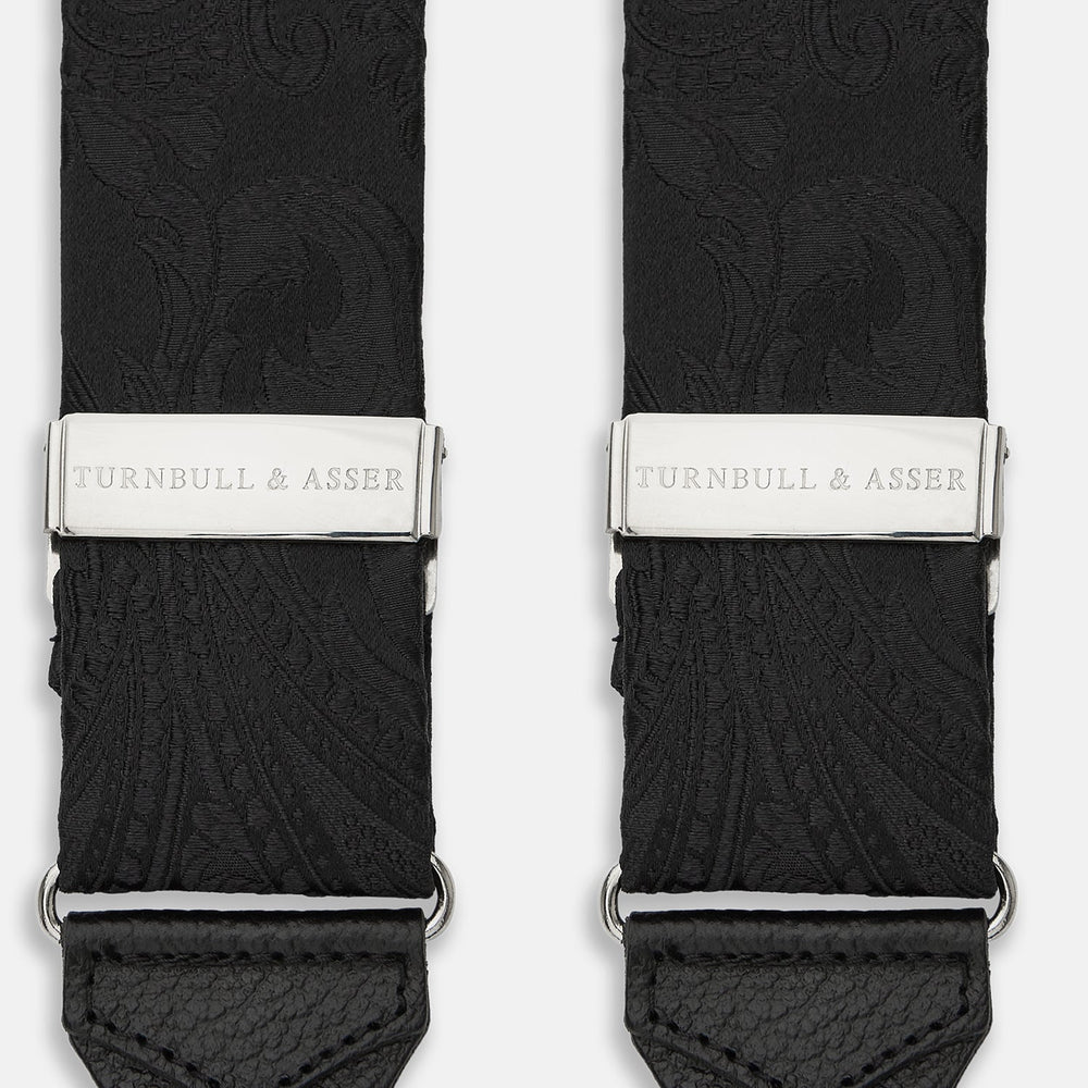 Turnbull & Asser's Black Paisley Adjustable Silk Braces feature silver-tone engraved clips and leather loop ends for button attachment, offering refined style. Shown against a white background.
