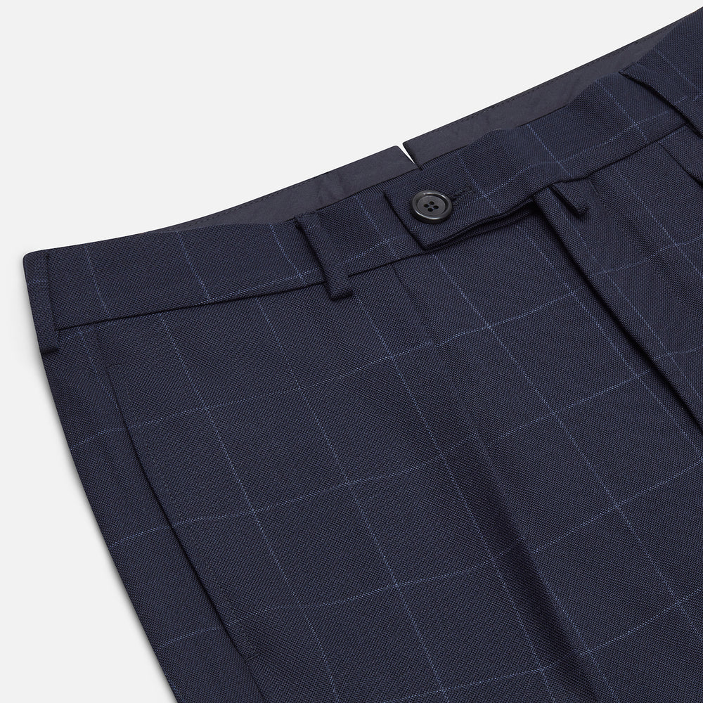 Turnbull & Asser Navy Check Edward Trousers feature a subtle white windowpane pattern, pleated front, belt loops, and button closure, shown against a plain white background.