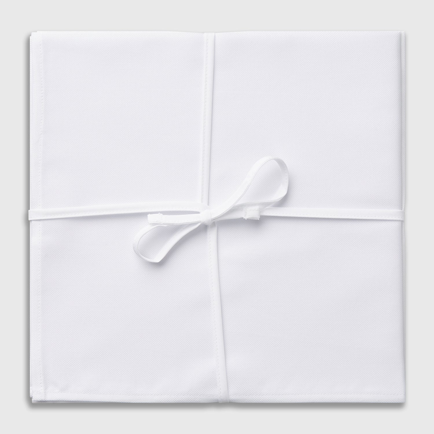 View 2 of product Three Turnbull & Asser Plain White Cotton Handkerchiefs from the 3-pack are neatly folded and overlapping on a light gray background.
