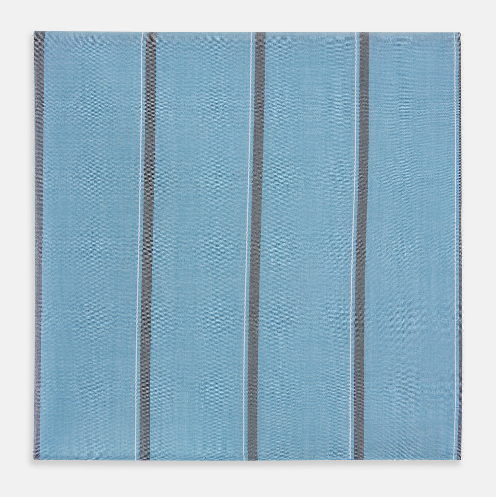 The Turnbull & Asser UK Cendre Blue Track Stripe Hand-Rolled Handkerchief is displayed folded against a plain background, showcasing its cendre blue color with a track stripe pattern—three vertical gray stripes and one thin light blue stripe—and expertly finished with meticulously hand-rolled edges.