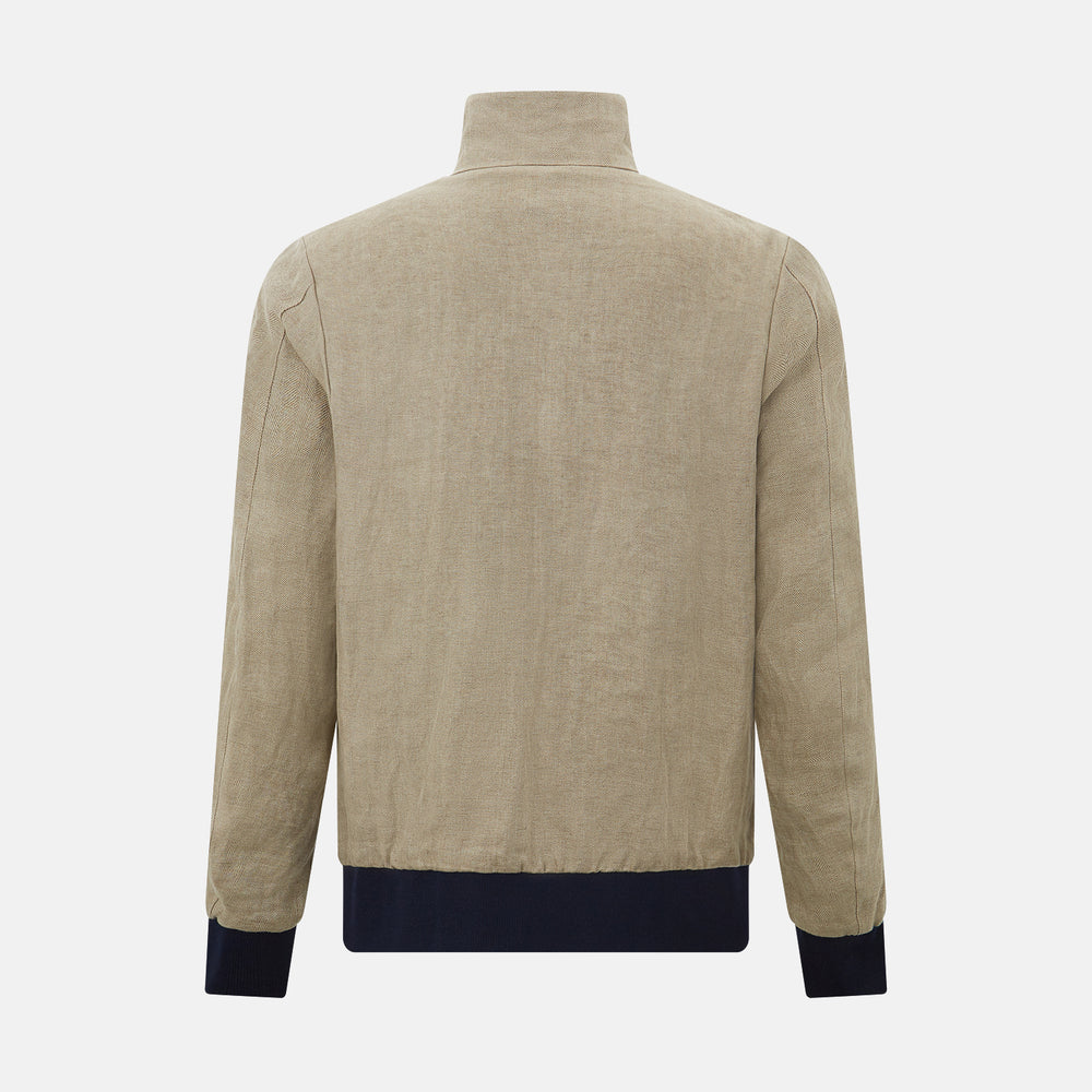 A Fairway Sand Golf Jacket in Linen by Turnbull & Asser UK, crafted from lightweight herringbone linen, features a front zipper, a chest zip pocket, two side zip pockets, and dark navy cuffs, collar lining, and waistband. Shown on a plain white background.