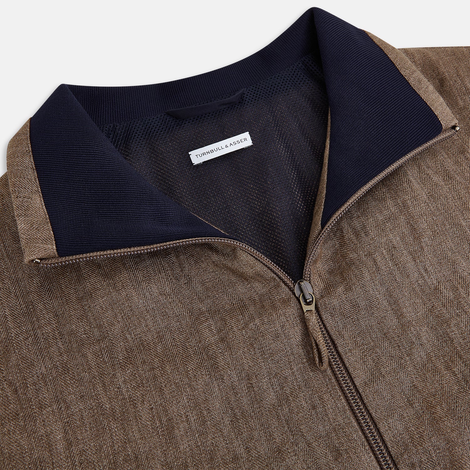 View 2 of product The Fairway Pinecone Golf Jacket in Linen by Turnbull & Asser UK is a brown zip-up jacket featuring a high collar, two side pockets, a zippered chest pocket, and dark cuffs and hem. Crafted from lightweight herringbone linen, it is displayed on a white background.