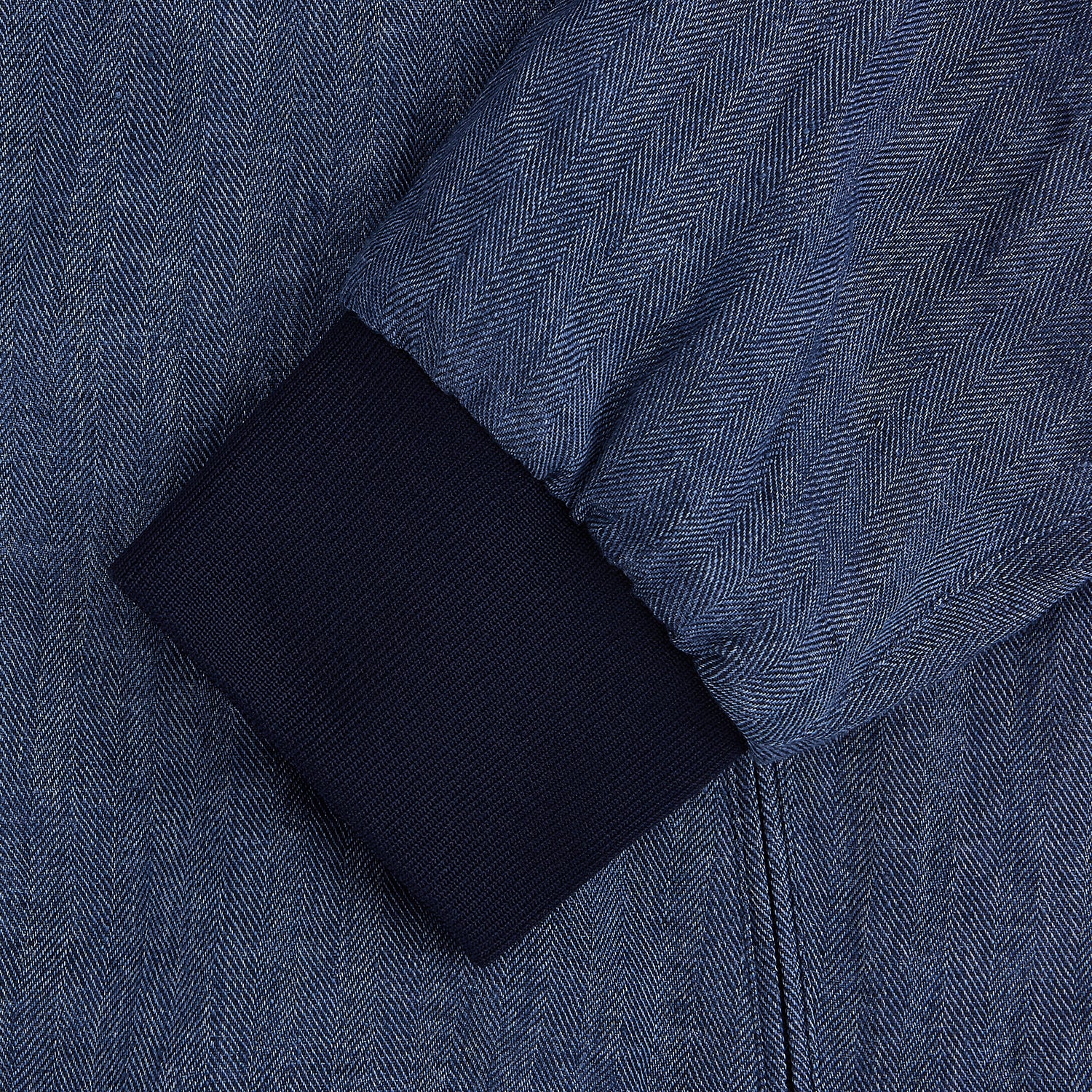 View 4 of product Introducing the Fairway Denim Golf Jacket in Linen by Turnbull & Asser UK—a blue zip-up jacket featuring a high collar, two side pockets, and a zippered chest pocket. The contrasting darker cuffs and hem accentuate its denim-like linen texture, making it the perfect versatile golf jacket for cooler days.