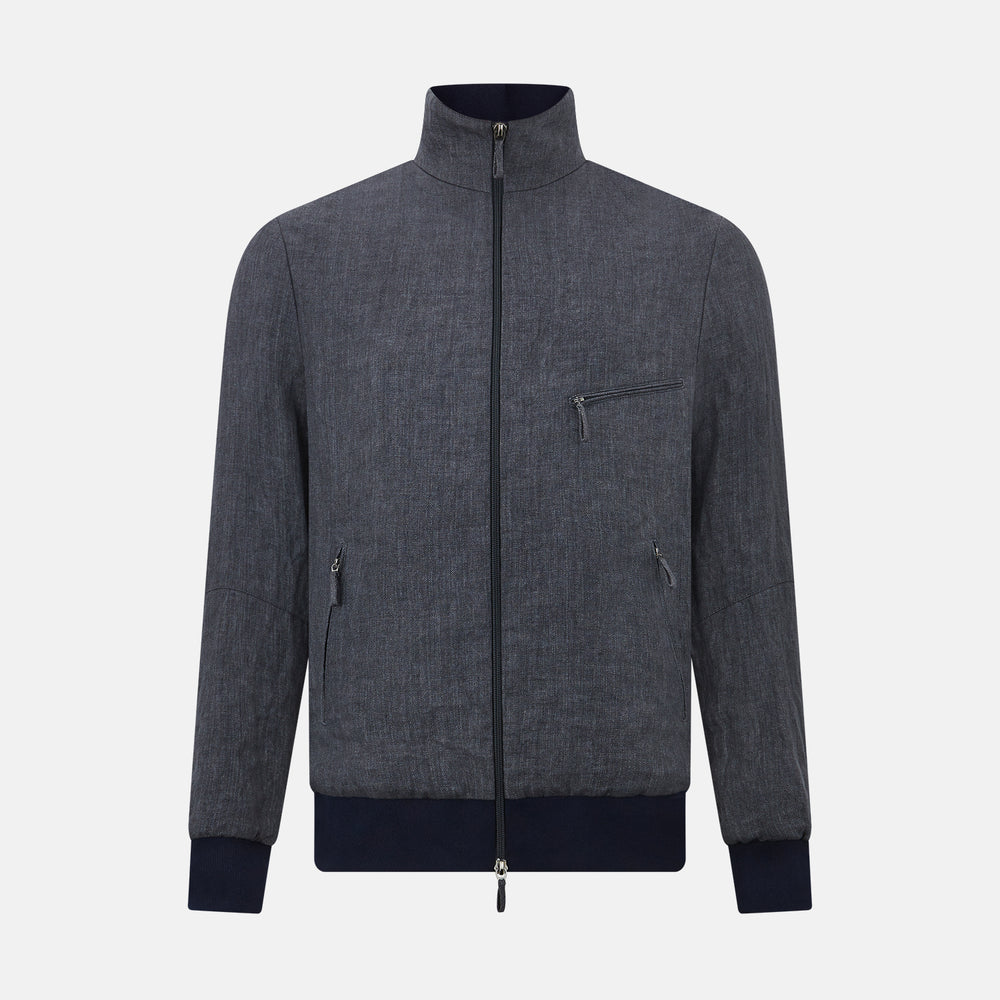 A front view of the Fairway Ash Golf Jacket in Linen by Turnbull & Asser UK is shown, featuring a high collar, two side zip pockets, a chest zip pocket, and black ribbed cuffs and hem. Crafted from lightweight gray herringbone linen for effortless warm-weather dressing, the jacket is displayed on a plain white background.