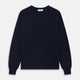 A luxurious navy crew neck cashmere jumper by Turnbull & Asser is laid flat on a white background, evoking timeless Scottish cashmere craftsmanship.
