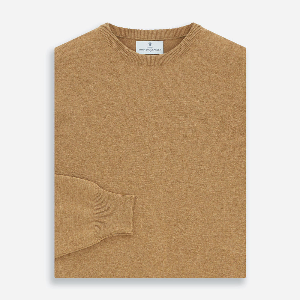 The Turnbull & Asser Camel Crew Neck Merino Wool Jumper is a classic, long-sleeve sweater in camel, laid flat on a white background. Featuring ribbed collar, cuffs, and hem, it’s an essential staple for every gentleman’s wardrobe.