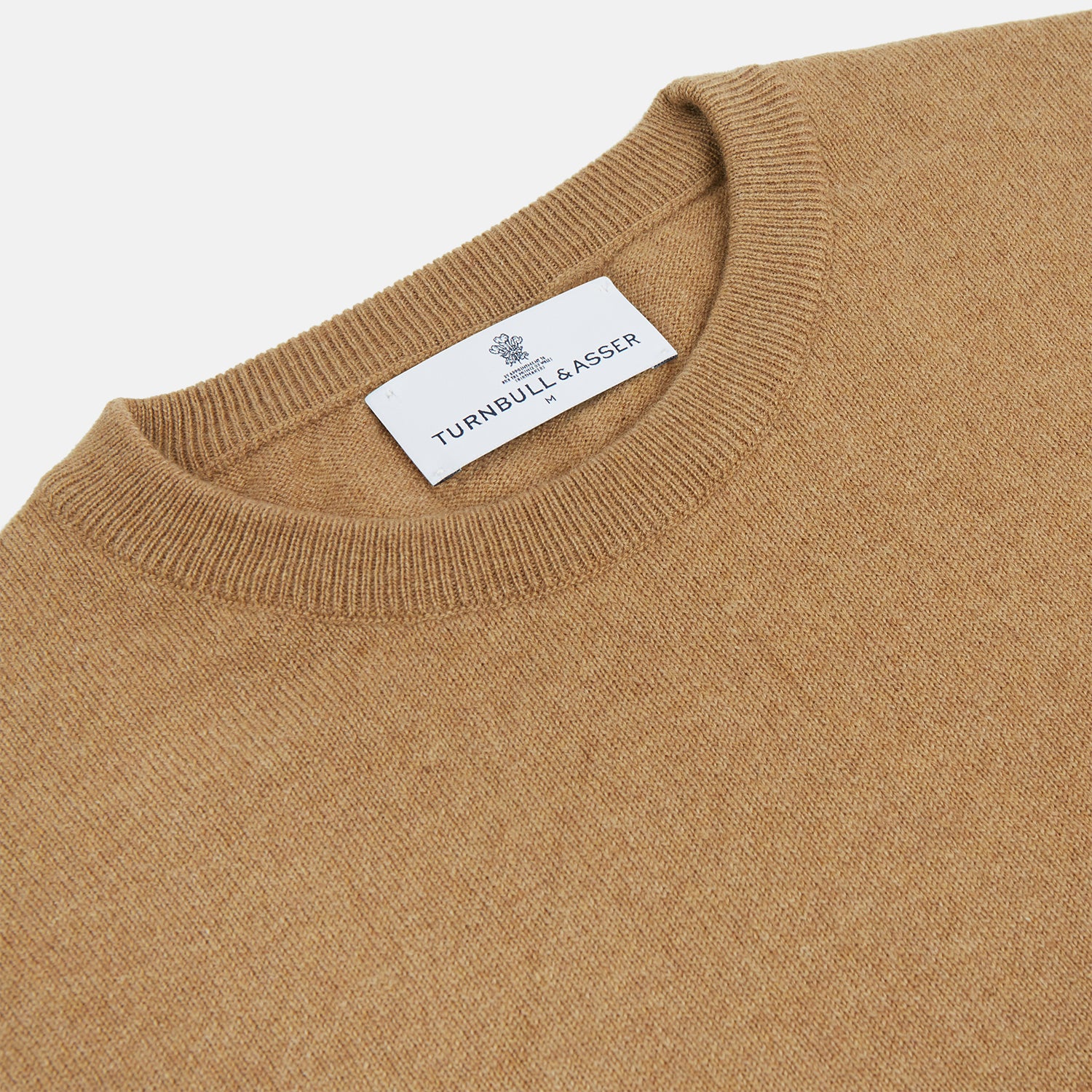 View 2 of product The Turnbull & Asser Camel Crew Neck Merino Wool Jumper is a classic, long-sleeve sweater in camel, laid flat on a white background. Featuring ribbed collar, cuffs, and hem, it’s an essential staple for every gentleman’s wardrobe.