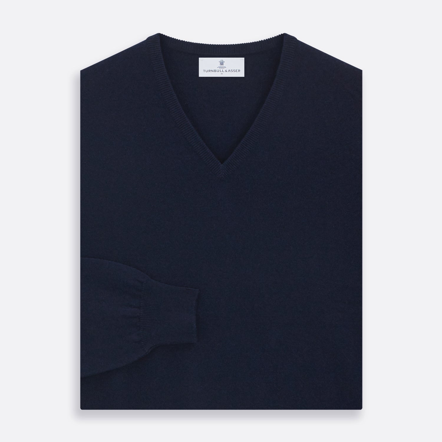 View 3 of product The Turnbull & Asser Navy V-Neck Cashmere Jumper, featuring long sleeves and ribbed cuffs and hem, is laid flat on a white background, showcasing its simple and classic design.