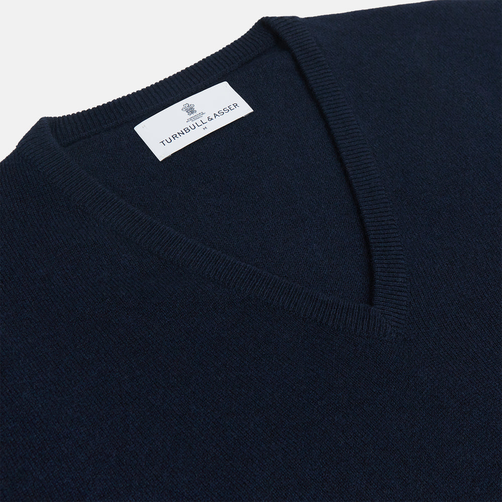 The Turnbull & Asser Navy V-Neck Cashmere Jumper, featuring long sleeves and ribbed cuffs and hem, is laid flat on a white background, showcasing its simple and classic design.